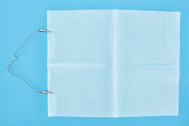 vista superior de avental dental com clipes metálicos isolados em azul
  - Foto, Imagem