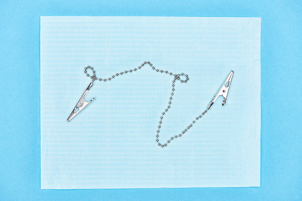 vista superior de clips metálicos en delantal dental aislado en azul
  - Foto, Imagen