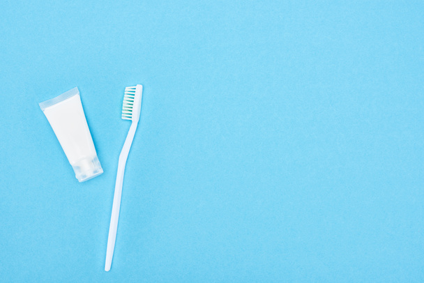 Κορυφαία θέα της λευκής οδοντόβουρτσα και οδοντόκρεμα απομονώνονται σε μπλε  - Φωτογραφία, εικόνα