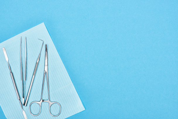 top view of metallic set with dental tools on apron isolated on blue  - Foto, immagini