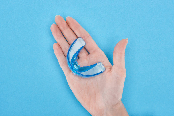 cropped view of woman holding retainer in hand isolated on blue  - Foto, immagini