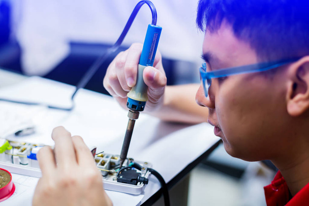 Asian technikus üzembe szemüveg és rögzítő elektromos aljzat kan - Fotó, kép