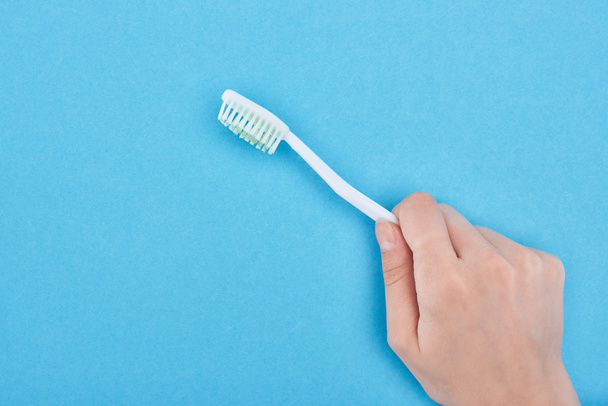 vista recortada de la mujer sosteniendo cepillo de dientes blanco aislado en azul
  - Foto, Imagen