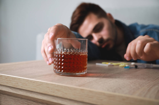 Homem inconsciente com dependência de álcool e drogas em casa
 - Foto, Imagem