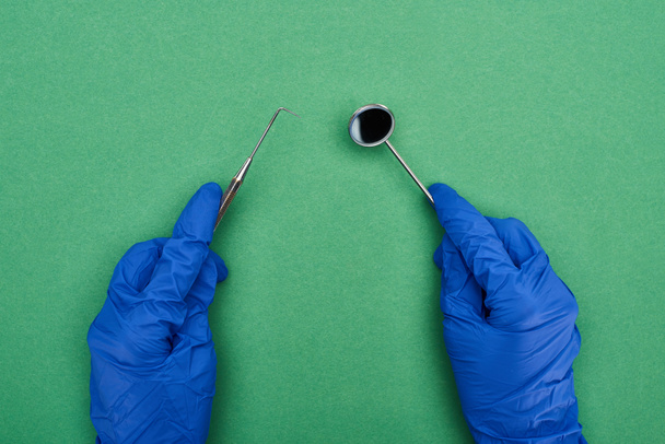 cropped view of dentist in latex gloves holding dental tools isolated on green  - Photo, Image
