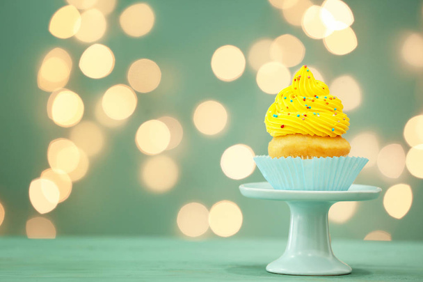 Zoete smakelijke Cupcake op tafel tegen gedeconcentreerde lichten - Foto, afbeelding
