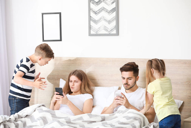 Kinderen scolding ouder met verslaving aan moderne technologieën in de slaapkamer - Foto, afbeelding