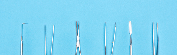 panoramic shot of set with metallic dental instruments isolated on blue  - Fotografie, Obrázek