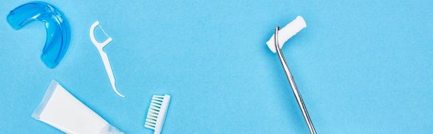 panoramic shot of tweezers with cotton pad near toothpaste and toothbrush on blue  - Photo, Image