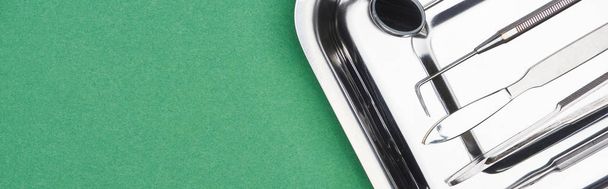 tiro panorâmico de conjunto inoxidável com instrumentos dentários isolados em verde
  - Foto, Imagem