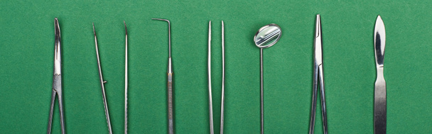 panoramic shot of set with stainless dental tools isolated on green  - Foto, afbeelding
