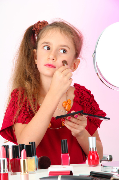 little girl in her mother's dress, is trying painting her face - 写真・画像