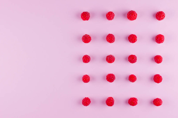 Pattern of raspberries on pink background. Colorful diet and healthy food concept. Background of raspberries. Top view. Flat lay. Copy space - Fotoğraf, Görsel