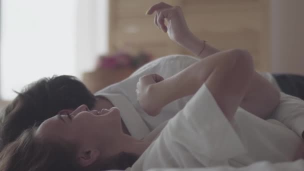 Happy young couple lying on the bed talking close-up. Beautiful girl showing her new yellow manicure to boyfriend. Tender relationship concept, people in love. Concept of happiness and tenderness. - Video