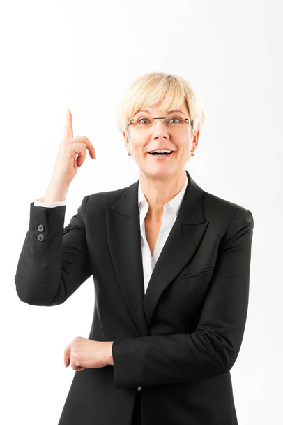 Щаслива зріла бізнес-леді вказує пальцем вгору
 - Фото, зображення