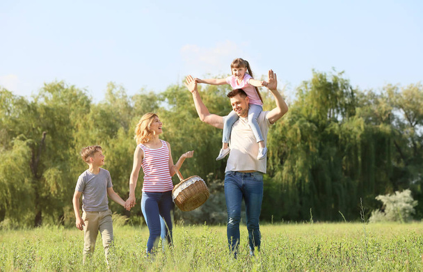 Ευτυχισμένη οικογένεια με τα πόδια στο πάρκο την καλοκαιρινή μέρα - Φωτογραφία, εικόνα