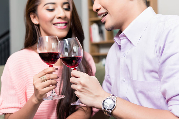 Hymyilevä pari paahtamalla punaiset viinilasit
 - Valokuva, kuva