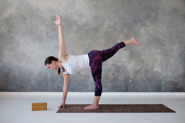 Frau praktiziert Yoga in verdrehter Halbmondübung, ardha chandrasana Pose. - Foto, Bild