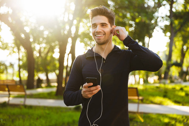 Portrait of handsome athletic man listening to music with earpho - Foto, Imagem