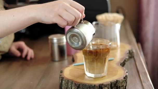 Barista pouring American coffee into a glass with ice and adding milk, whipped cream and ice cream. barista preparing coffee frappe in a cafe. Soft focus - Metraje, vídeo