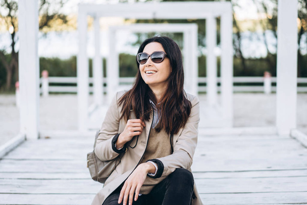 Pretty long hair brunette girl in sunglasses relaxing outdoor. - Фото, изображение