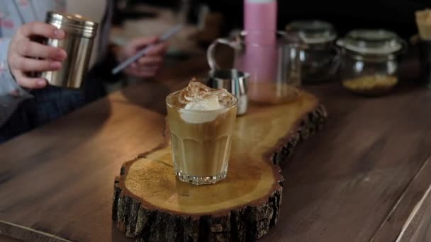 Barista Amerikaanse koffie gieten in een glas met ijs en het toevoegen van de melk, slagroom en ijs. Barista koffie in een café frappe voorbereiden. Soft Focus Sea... - Video