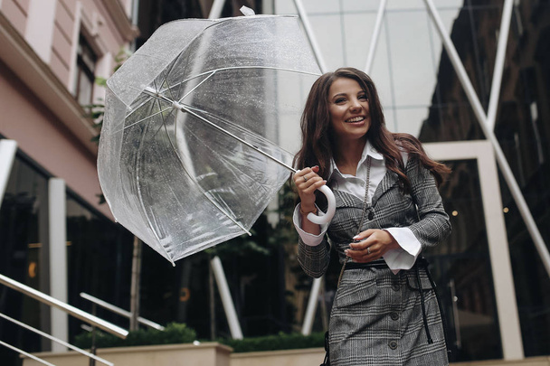 Portrait of a laughing happy woman under an umbrella near the office. Copy space on the left side. It's spring rain. - Fotoğraf, Görsel
