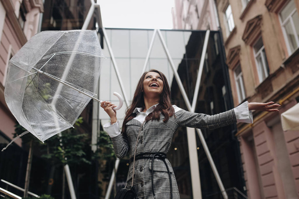Porträt einer lachenden glücklichen Frau unter einem Regenschirm in der Nähe der - Foto, Bild