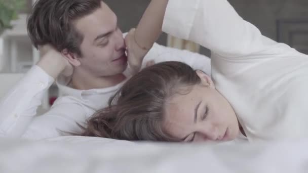 Young couple lying in bed close-up. Girl offended and turned away from the man. Difficulties in the relationship between man and woman. Side view - Imágenes, Vídeo