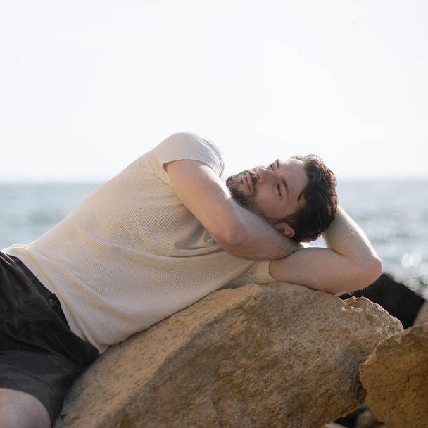 Handsome in love man outdoor portrait lying on a rocks and dreaming - Photo, Image