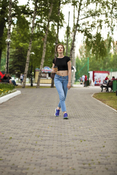 Young beautiful brunette girl in jeans and t-shirt walking in su - Foto, afbeelding