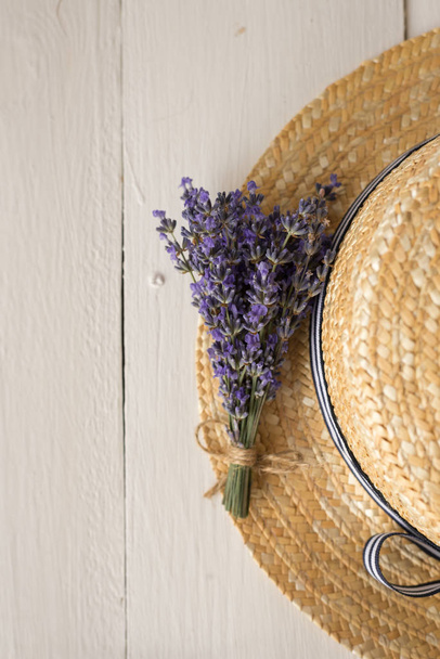 Een miniatuur zomer Provençaalse compositie. Een geurig boeket van lavendel ligt op een stro hoed. - Foto, afbeelding