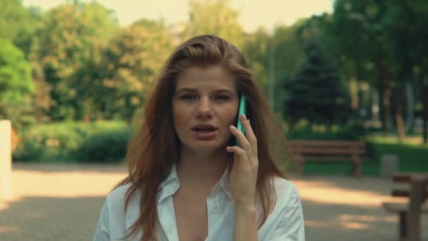 ginger girl wearing white shirt has phone conversatio - Materiał filmowy, wideo