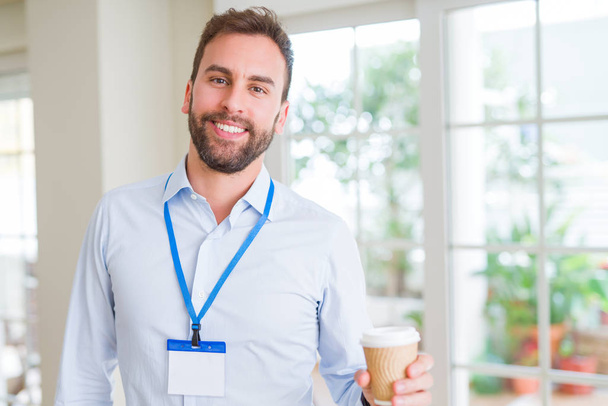 Bonito homem de negócios vestindo saco de id com um grande sorriso no rosto enquanto bebe tirar café em uma xícara de papel
 - Foto, Imagem