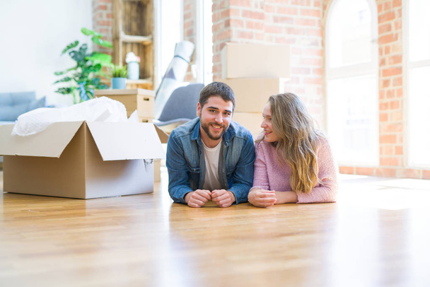 Молода красива пара в любові розслабляється лежачи на підлозі разом з картонними коробками навколо для переїзду в новий будинок
 - Фото, зображення