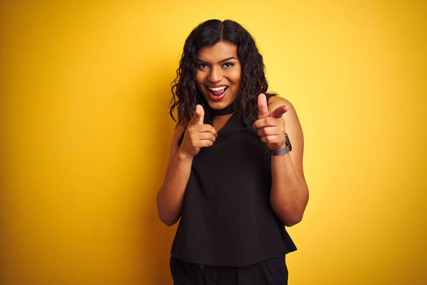 Transsexual transgender elegant businesswoman standing over isolated yellow background pointing fingers to camera with happy and funny face. Good energy and vibes. - Foto, imagen
