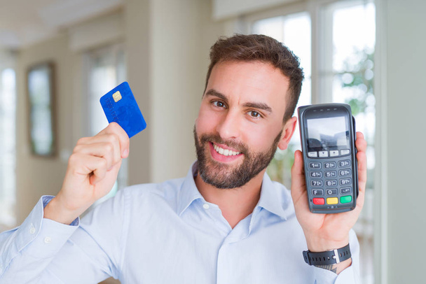 Bonito homem de negócios segurando terminal pos e cartão de crédito, compra e pagamento usando dataphone
 - Foto, Imagem