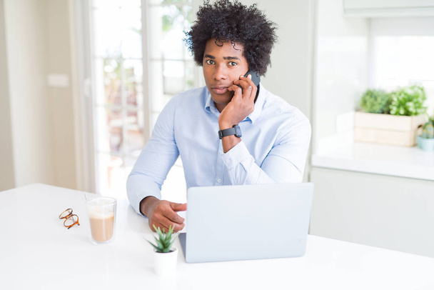 Uomo d'affari afroamericano che parla al telefono con un'espressione fiduciosa sul viso intelligente pensando seriamente
 - Foto, immagini