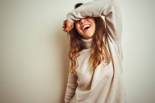 Mujer hermosa joven vistiendo suéter de invierno de pie sobre fondo blanco aislado cubriendo los ojos con el brazo sonriendo alegre y divertido. Concepto ciego
. - Foto, Imagen