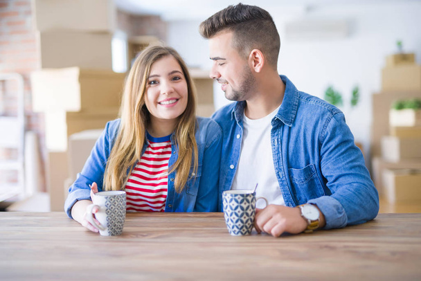junges Paar trinkt eine Tasse Kaffee und freut sich über den Umzug in ein neues Zuhause - Foto, Bild