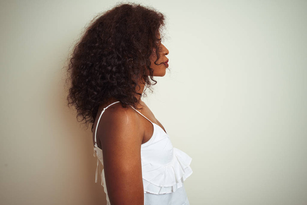 Młoda African American kobieta ubrana w t-shirt stojący na białym tle patrząc na bok, zrelaksować się profil poza naturalną twarz z ufnością uśmiech. - Zdjęcie, obraz