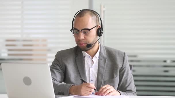 Agente de soporte al cliente africano serio con auriculares hablando con el cliente
 - Metraje, vídeo