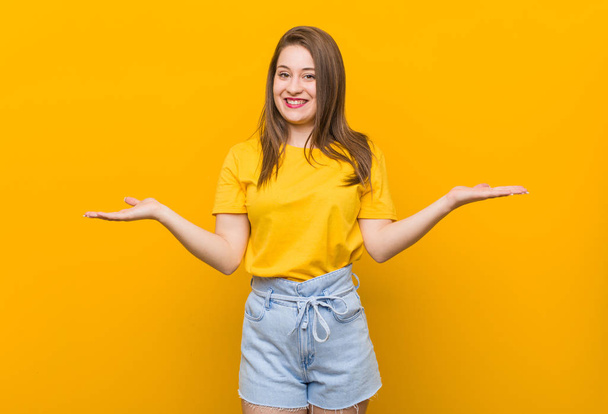 Jonge vrouw tiener het dragen van een geel shirt met een welkome uitdrukking. - Foto, afbeelding