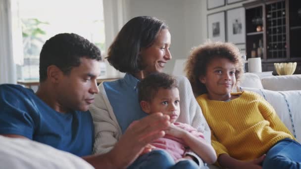 Молода сім'я сидить разом на дивані у своїй вітальні дивитися телевізор і говорити, крупним планом
 - Кадри, відео