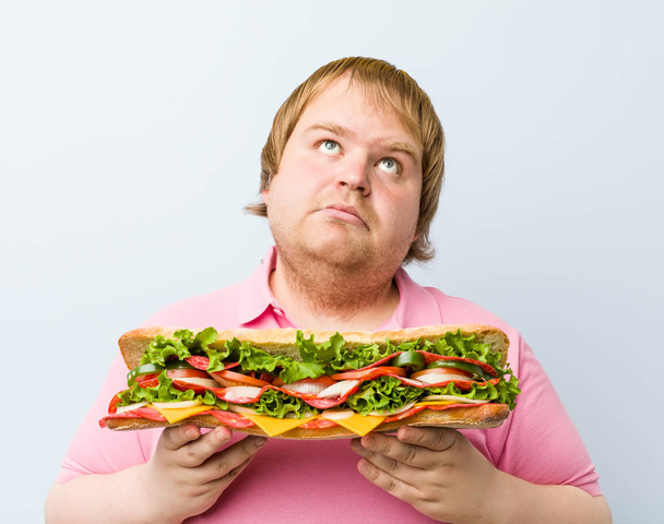 Kavkazský blázen blonďatý tlustý muž držící obrovský sendvič - Fotografie, Obrázek