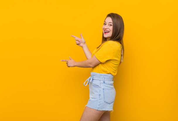 若い女性ティーンエイジャーは、人差し指を離して興奮して黄色のシャツを着て興奮. - 写真・画像