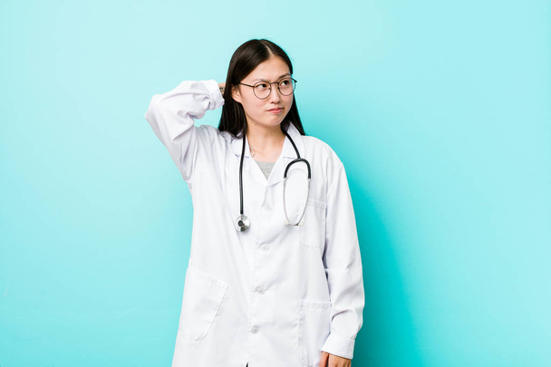 junge chinesische Ärztin berührt Hinterkopf, denkt nach und trifft eine Entscheidung. - Foto, Bild