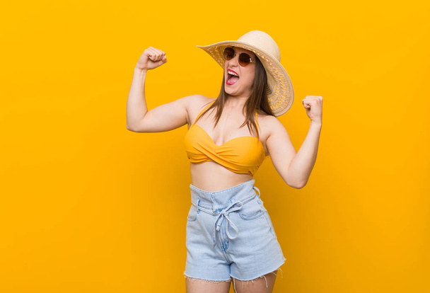 Young caucasian woman wearing a straw hat, summer look raising fist after a victory, winner concept. - Fotografie, Obrázek