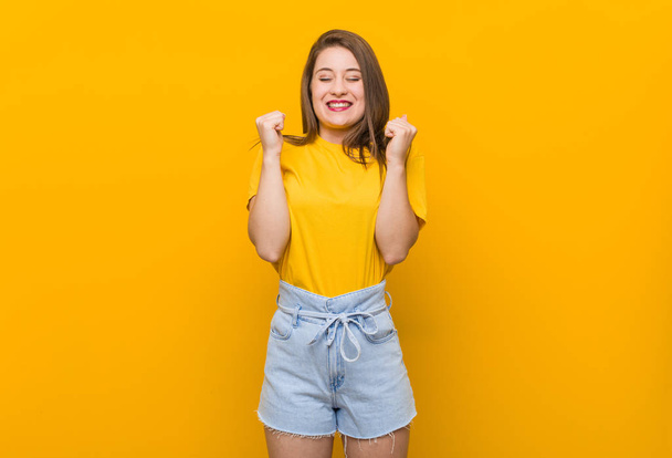 Młoda kobieta Nastolatka ubrana w żółtą koszulę podnosząc pięść, uczucie szczęśliwości i sukcesu. Koncepcja zwycięstwa. - Zdjęcie, obraz