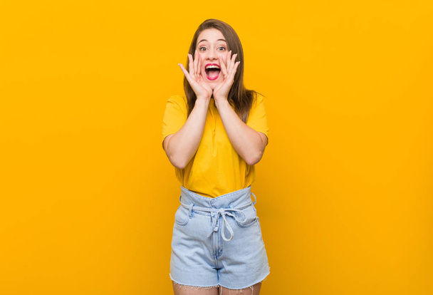 Jonge vrouw tiener het dragen van een geel shirt schreeuwen opgewonden naar voren. - Foto, afbeelding